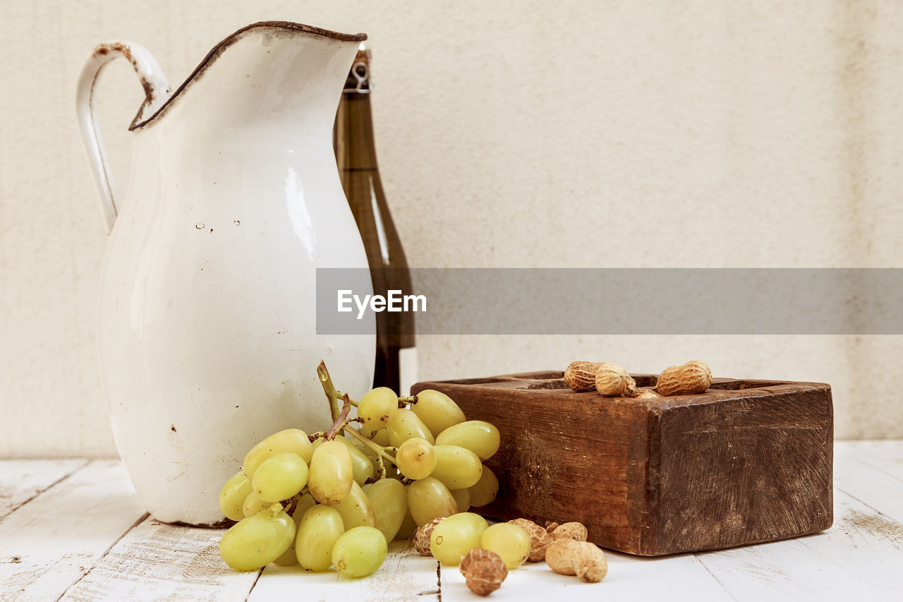 Close-up of grapes by pitcher and peanuts on table