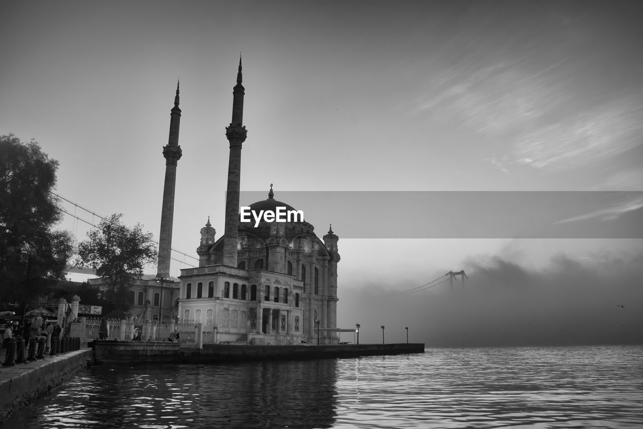 View of buildings at waterfront against sky and fog