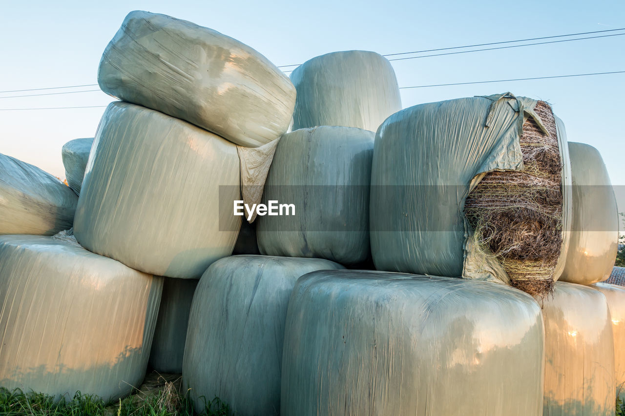 CLOSE-UP OF HAY BALES ON FIELD AGAINST CLEAR SKY