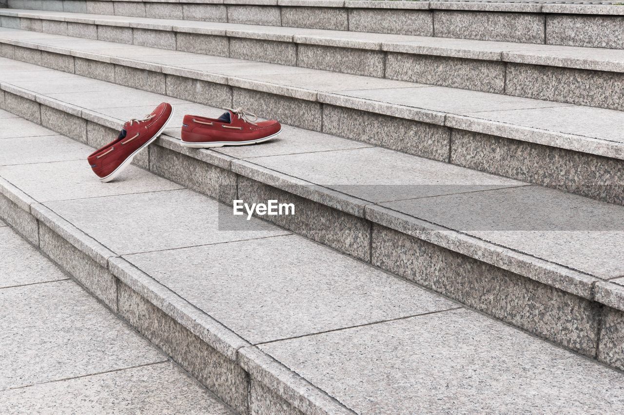 Pair of red shoes seemingly climbing a set of wide concrete steps, without people.