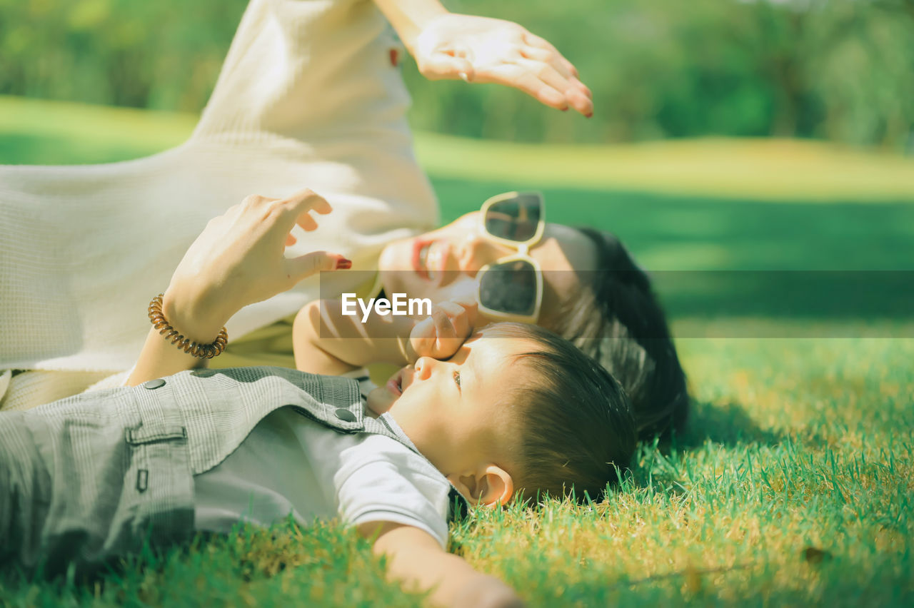 Mother and son lying on grass at park