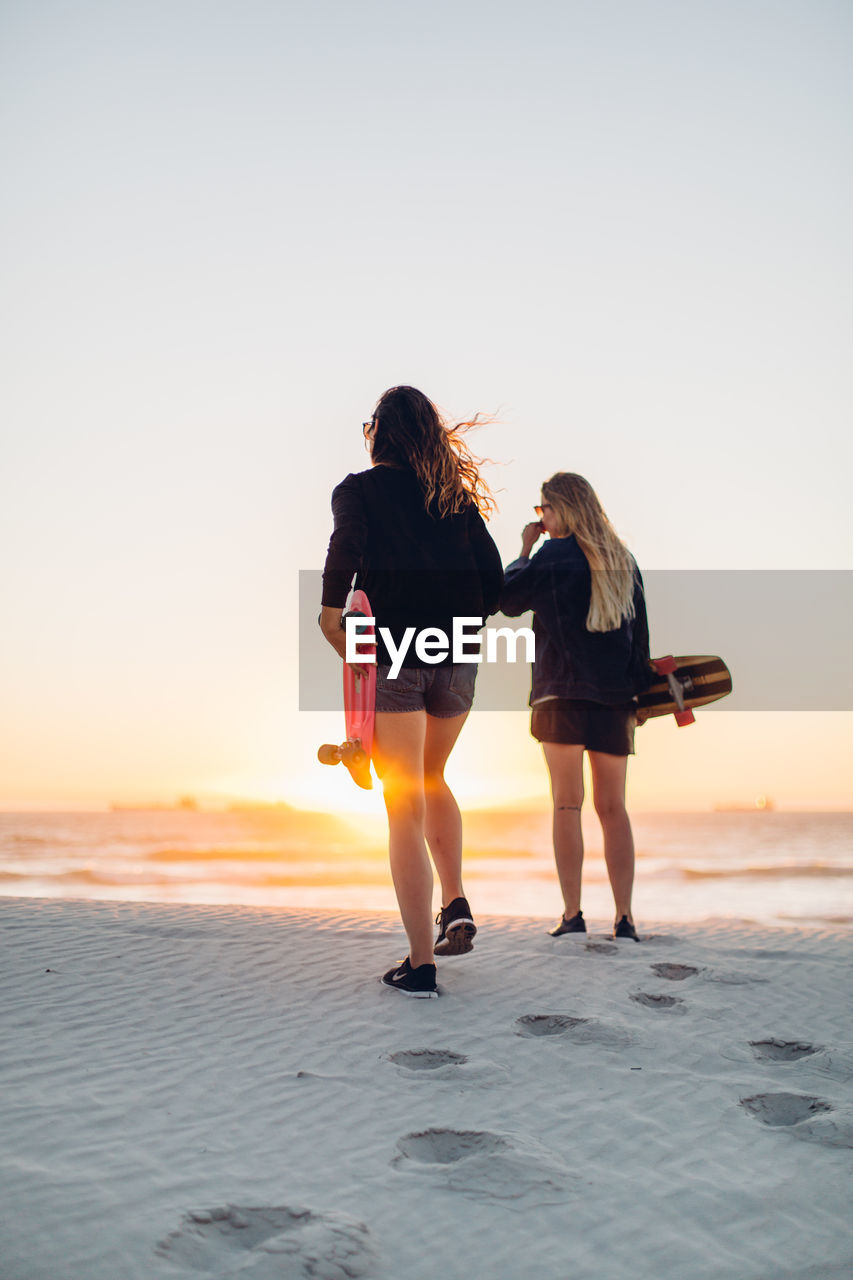 FULL LENGTH REAR VIEW OF WOMAN WALKING ON BEACH AGAINST CLEAR SKY