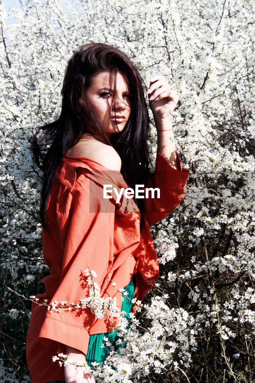 Portrait of young woman standing amidst flowering plants