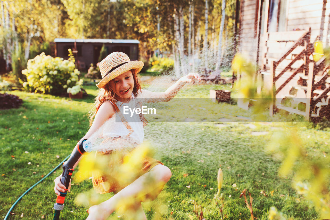 Smiling girl watering plants in garden