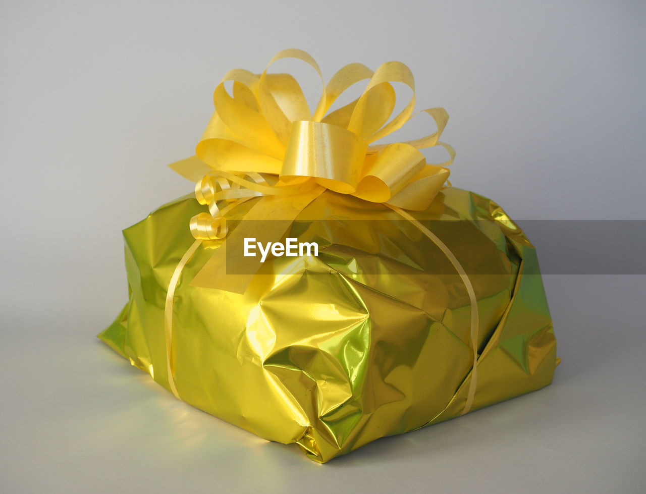 yellow, studio shot, gift, paper, gold, petal, flower, indoors, art, gray background, celebration, no people, single object, ribbon, origami paper, surprise, origami, wrapping paper, shiny, wrapped, wealth, gray, cut out, bow, luxury, box, emotion, holiday, colored background, tied bow, event