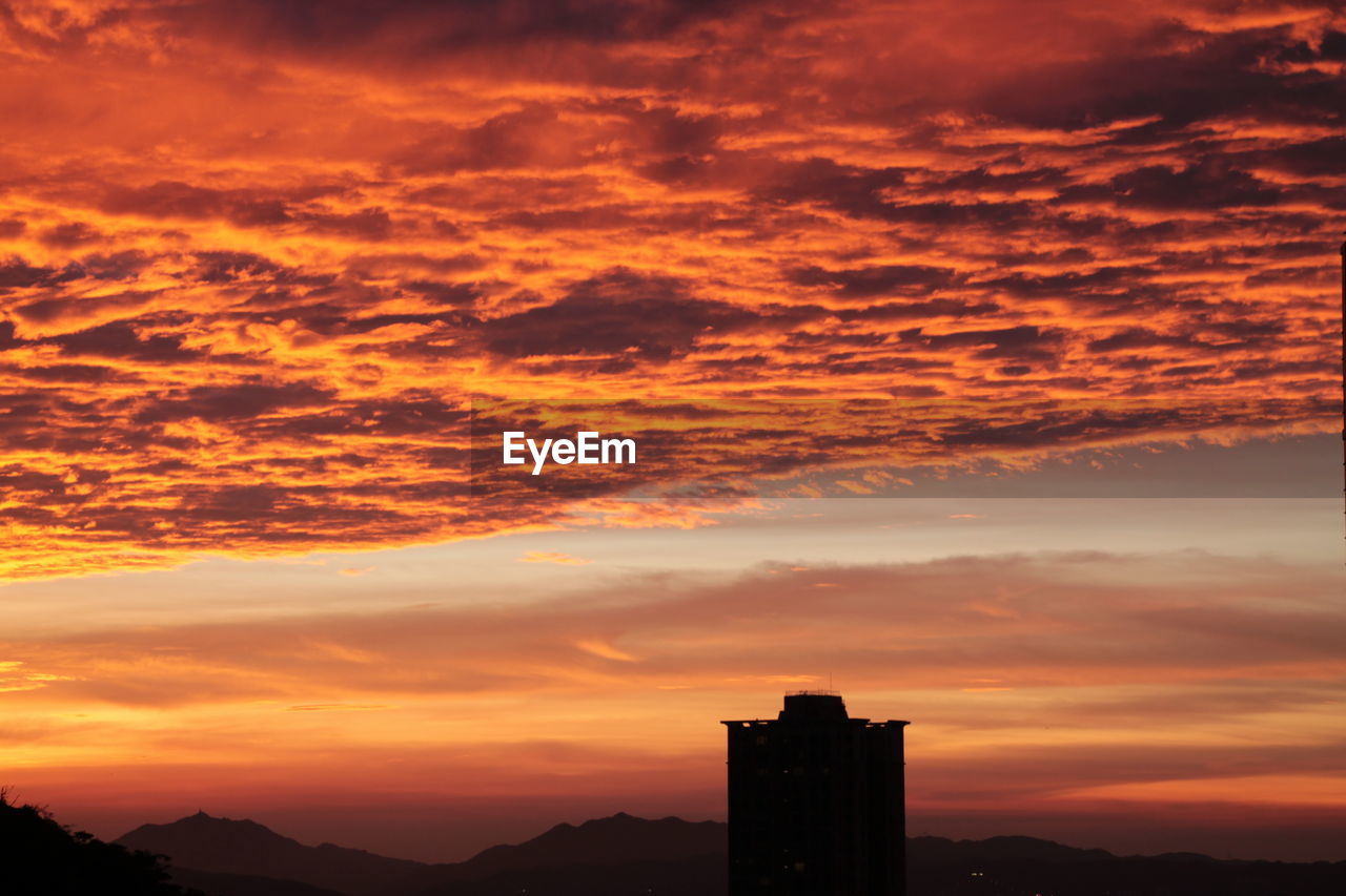 sky, sunset, cloud, afterglow, architecture, horizon, built structure, red sky at morning, dawn, dramatic sky, building exterior, nature, silhouette, landscape, city, beauty in nature, orange color, building, scenics - nature, evening, travel destinations, environment, no people, outdoors, sunlight, urban skyline, cloudscape, sun, travel, moody sky, tranquility, mountain, cityscape, romantic sky, atmospheric mood, tourism, skyline
