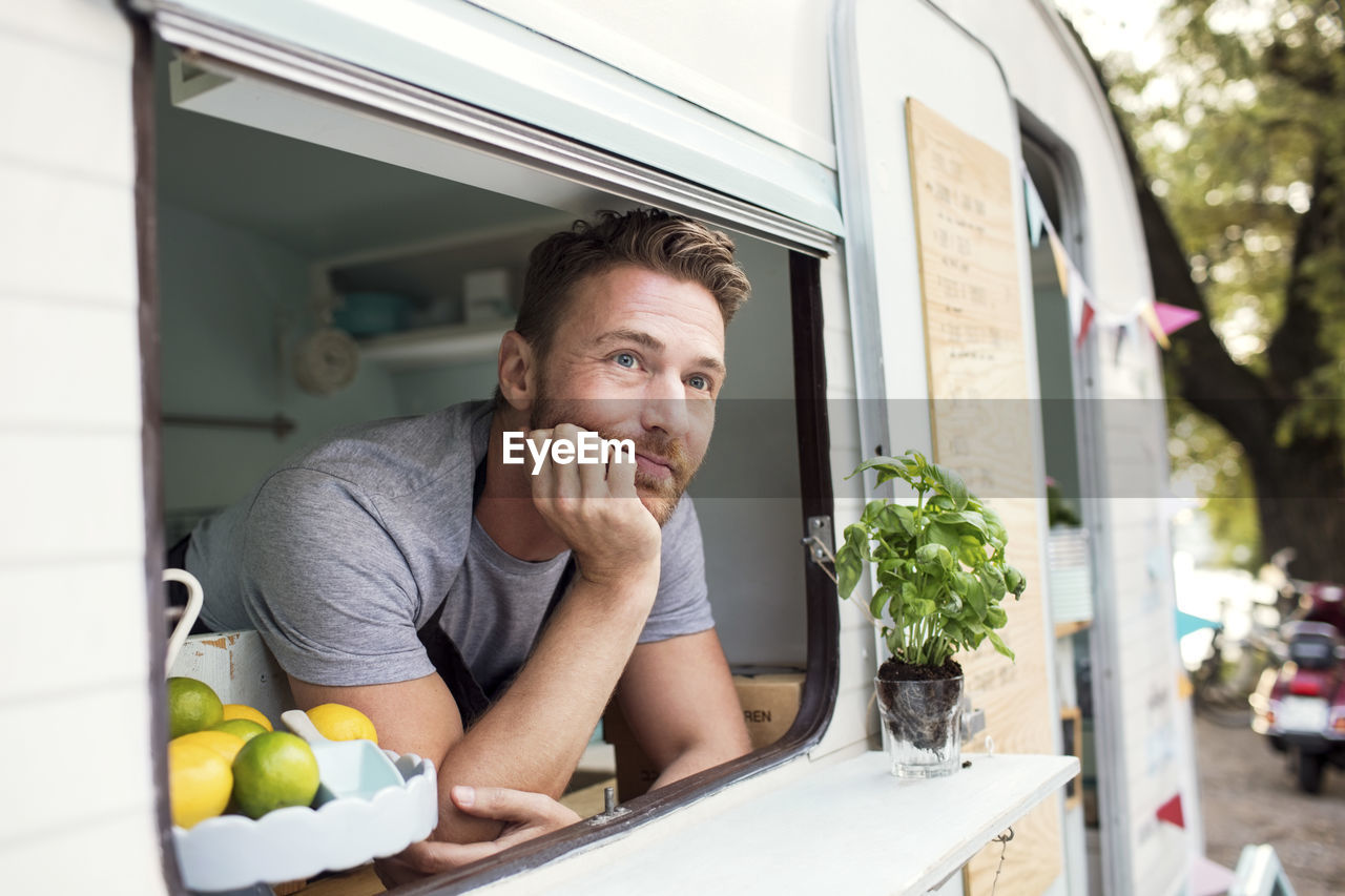 Thoughtful male owner looking out through food truck window
