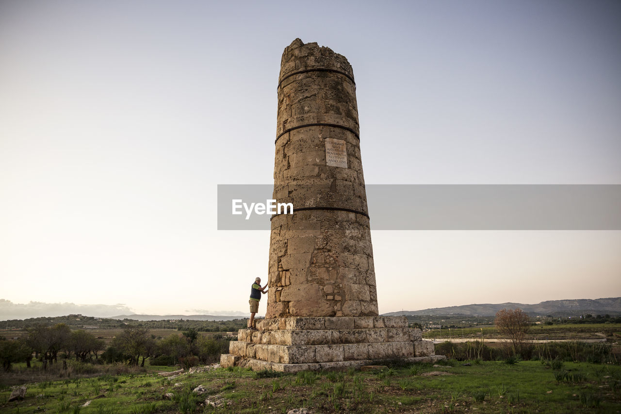 Italy, sicily, helorus, senior man standing at a column of a hellenistic tomb