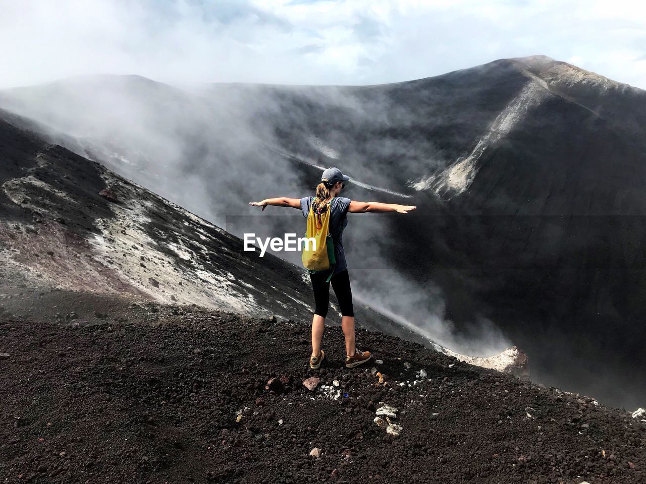 MAN WITH ARMS OUTSTRETCHED STANDING ON ROCK