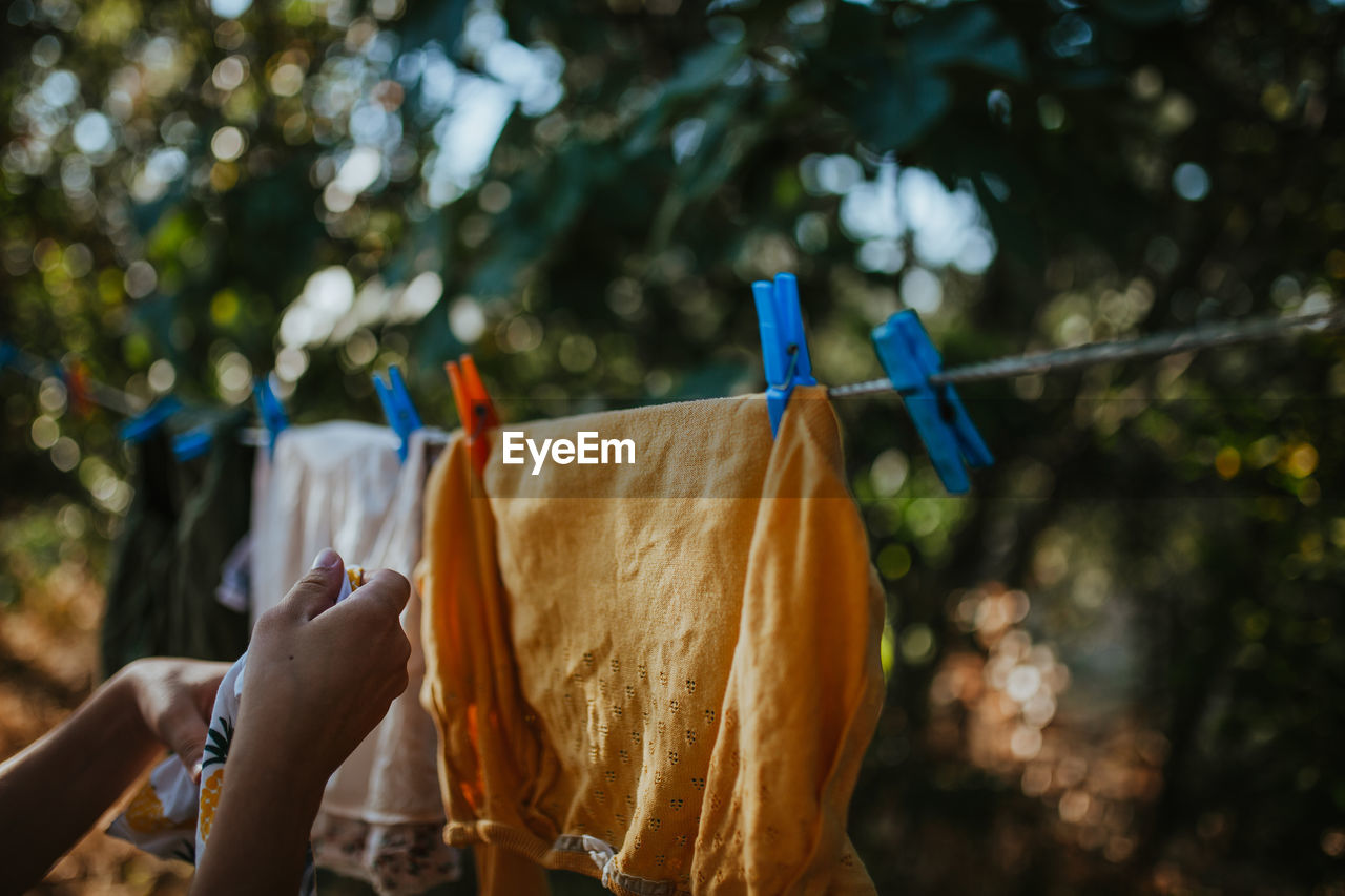 Cropped hand of woman drying clothes on clothesline