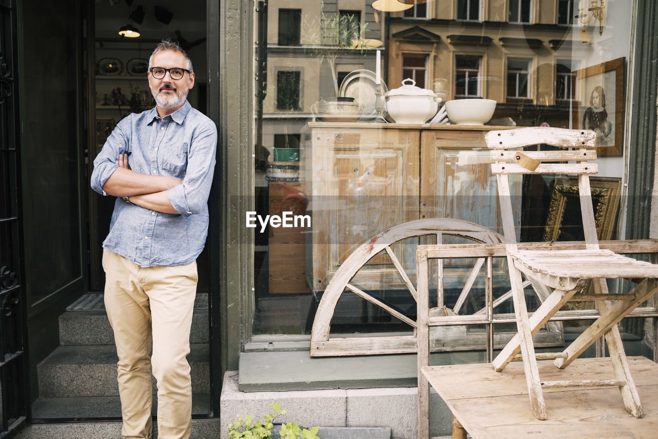 Confident owner standing on entrance of antique shop