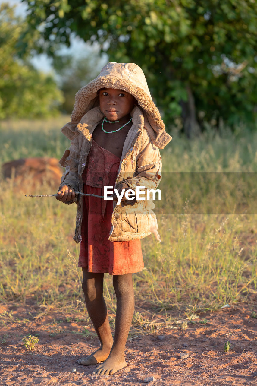 FULL LENGTH PORTRAIT OF WOMAN STANDING IN FIELD