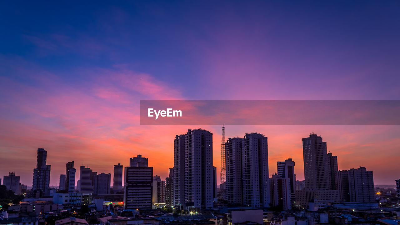 Modern buildings against sky during sunset