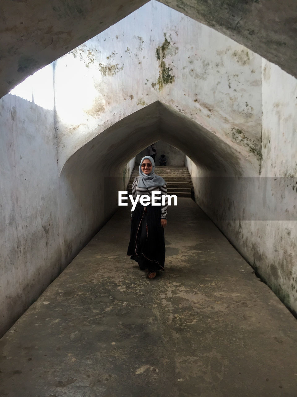 Rear view of woman walking in tunnel