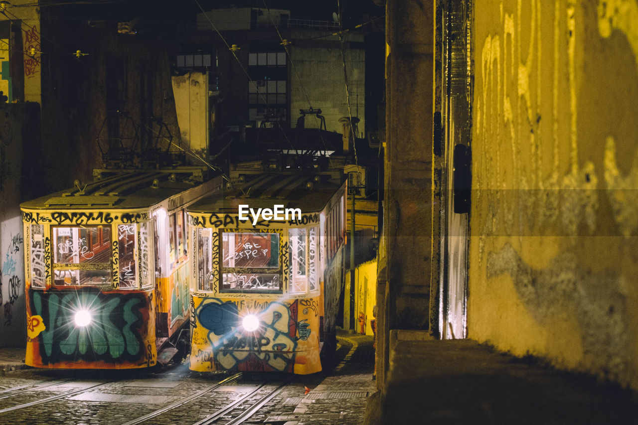 ILLUMINATED STREET AMIDST BUILDINGS IN CITY