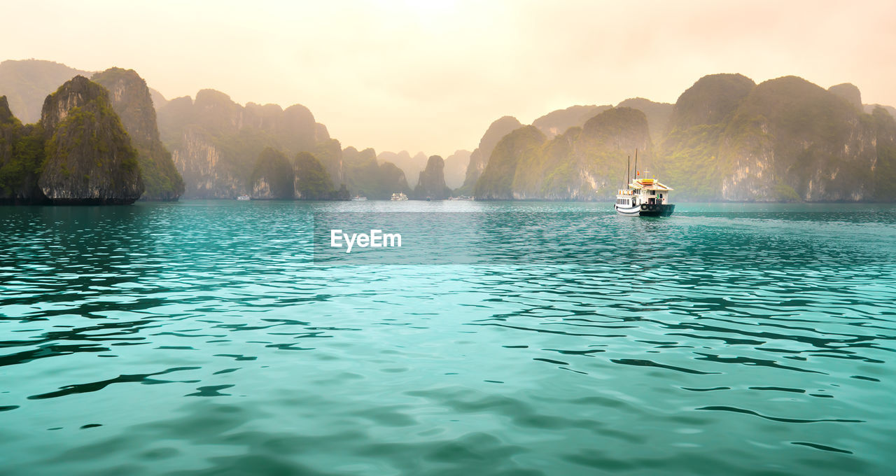 PEOPLE SAILING ON SEA AGAINST MOUNTAIN