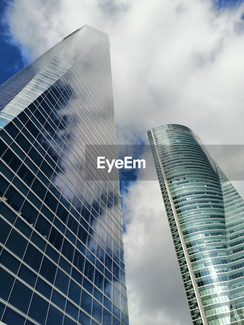 LOW ANGLE VIEW OF MODERN GLASS BUILDING AGAINST SKY