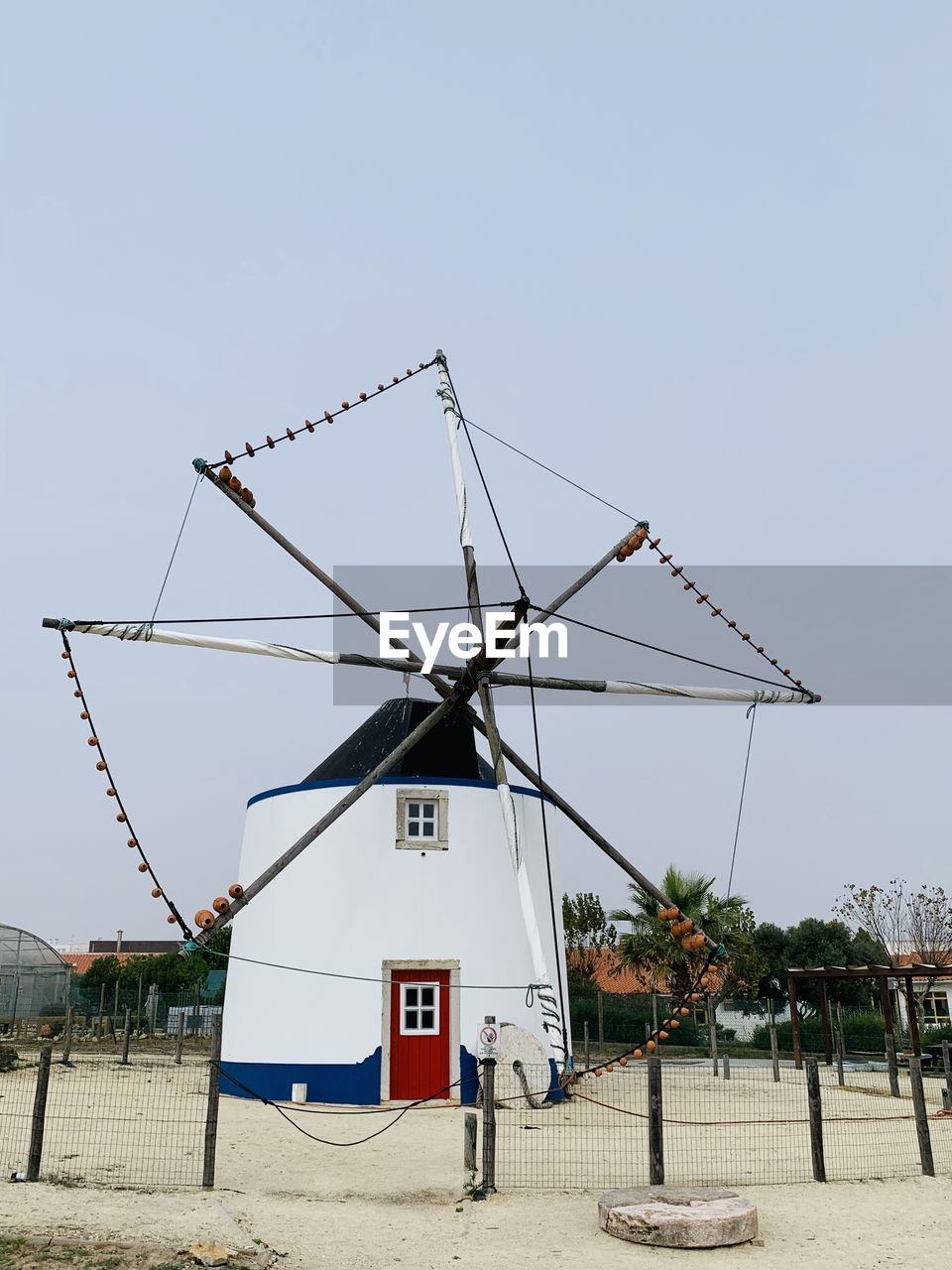 Traditional white windmill on beach against clear sky