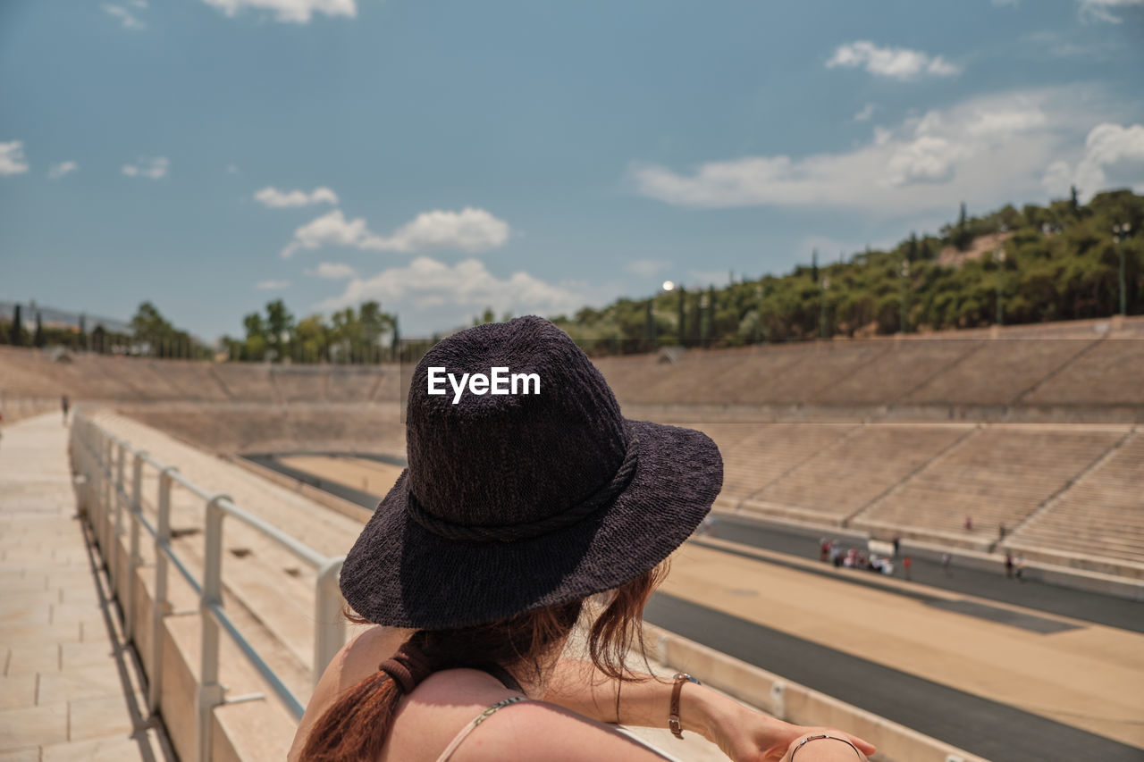 REAR VIEW OF WOMAN WITH UMBRELLA ON RAILING