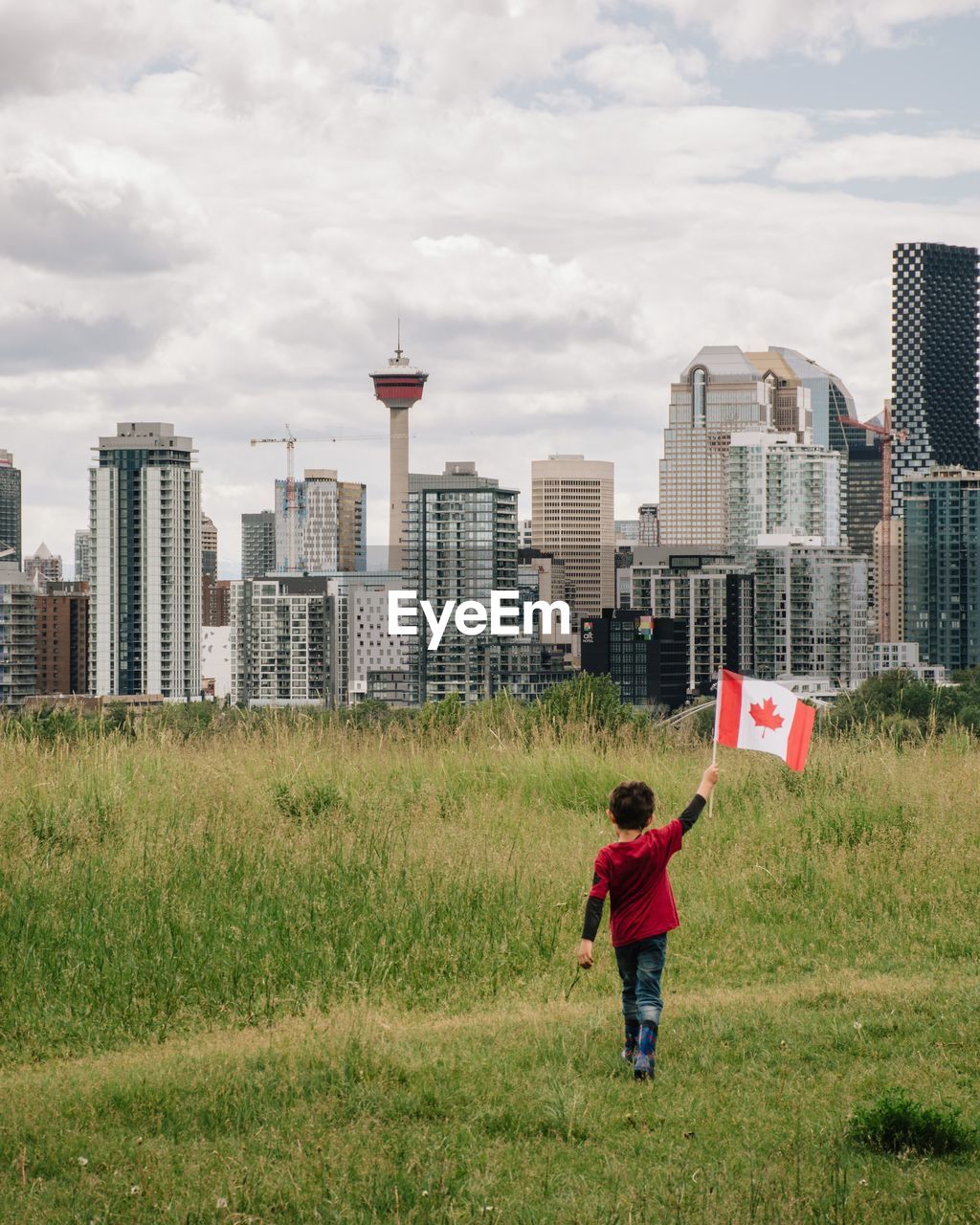 Young boy holding a canadian flag with calgary downtown in the background