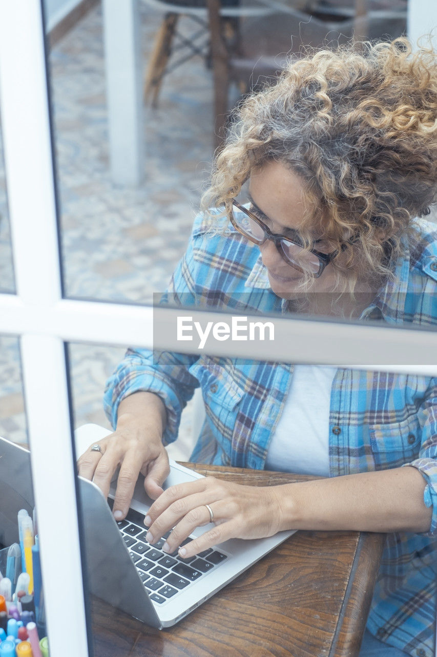 rear view of woman using laptop on table