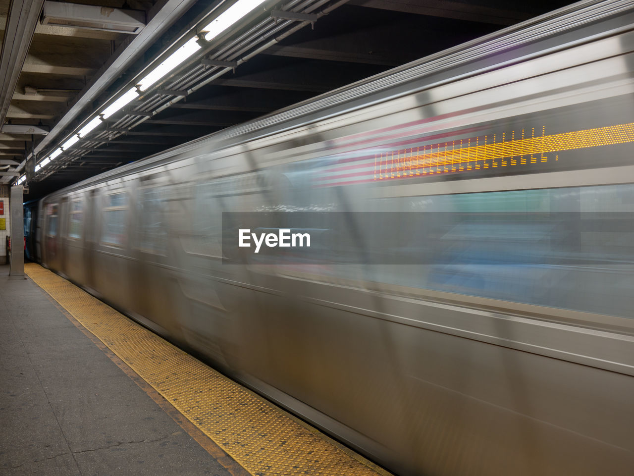 BLURRED MOTION OF TRAIN AT RAILROAD STATION PLATFORM