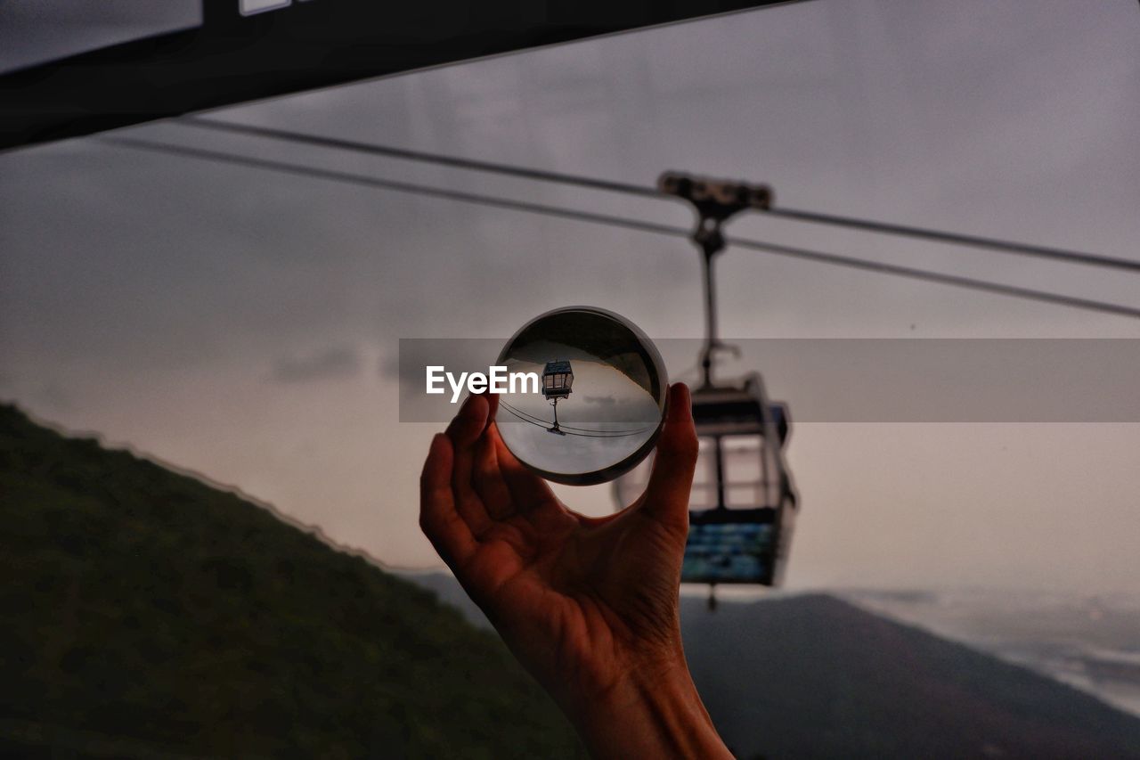 CLOSE-UP OF PERSON HOLDING GLASS AGAINST SKY