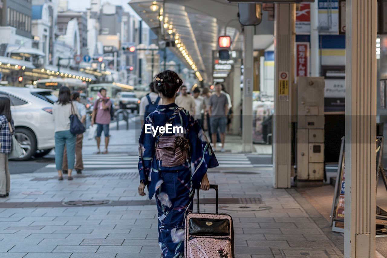 Rear view of woman in traditional clothe walking on street in city, going to travel 