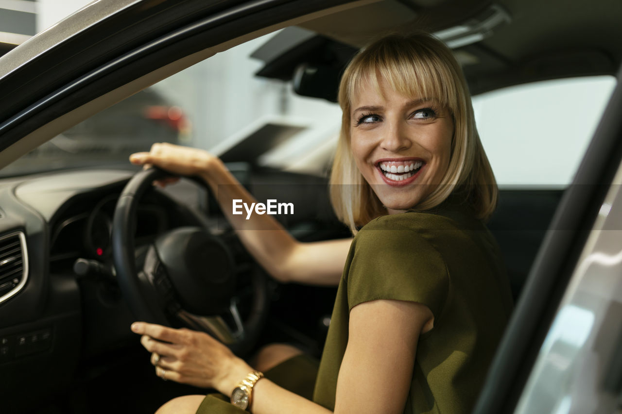 Blond woman choosing new car in car dealership
