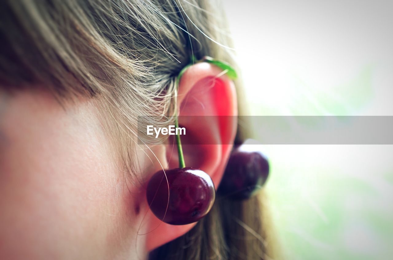Close-up of woman with cherries on ear