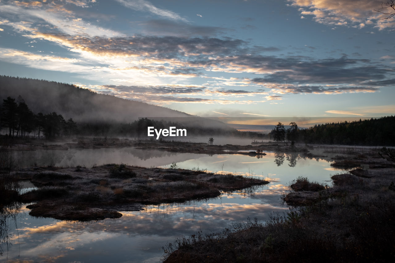 Picturesque natural landscape panorama in norway with mist rising above water and cloudscape