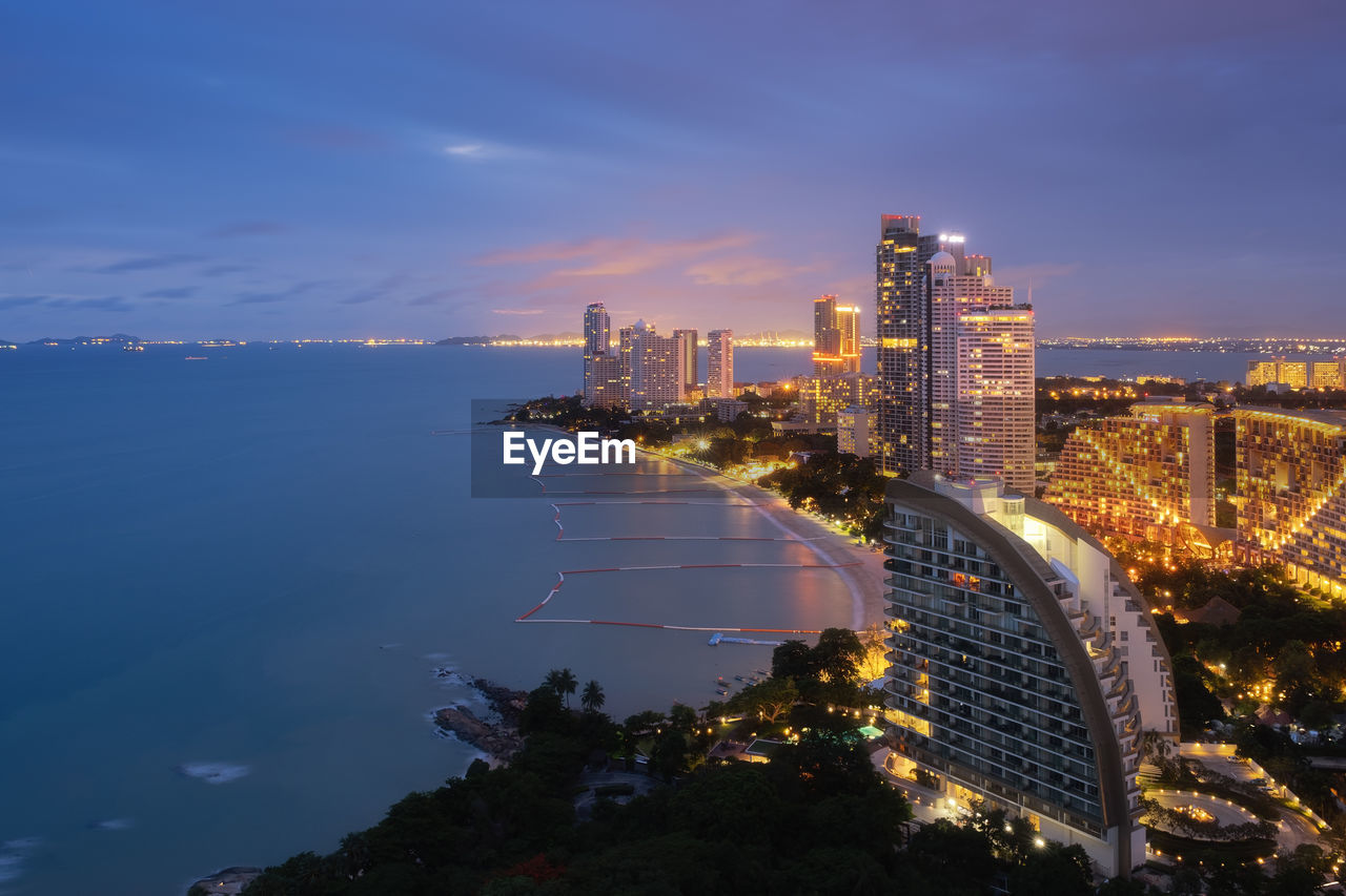 HIGH ANGLE VIEW OF ILLUMINATED CITY BY BUILDINGS AGAINST SKY