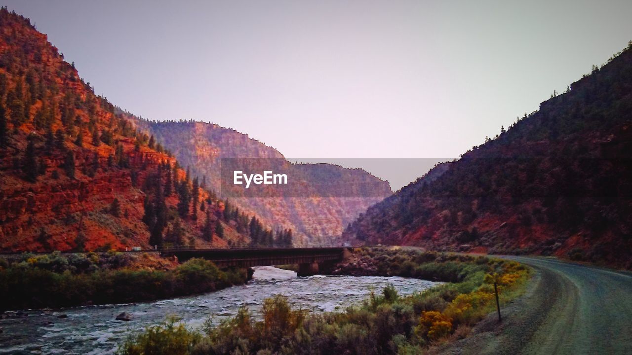 RIVER AMIDST MOUNTAINS AGAINST CLEAR SKY