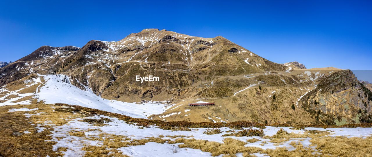 Scenic view of snowcapped mountains against clear blue sky