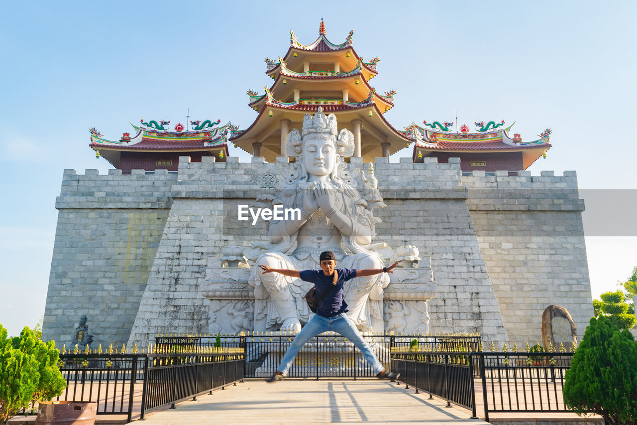 Man jumping against statue in city