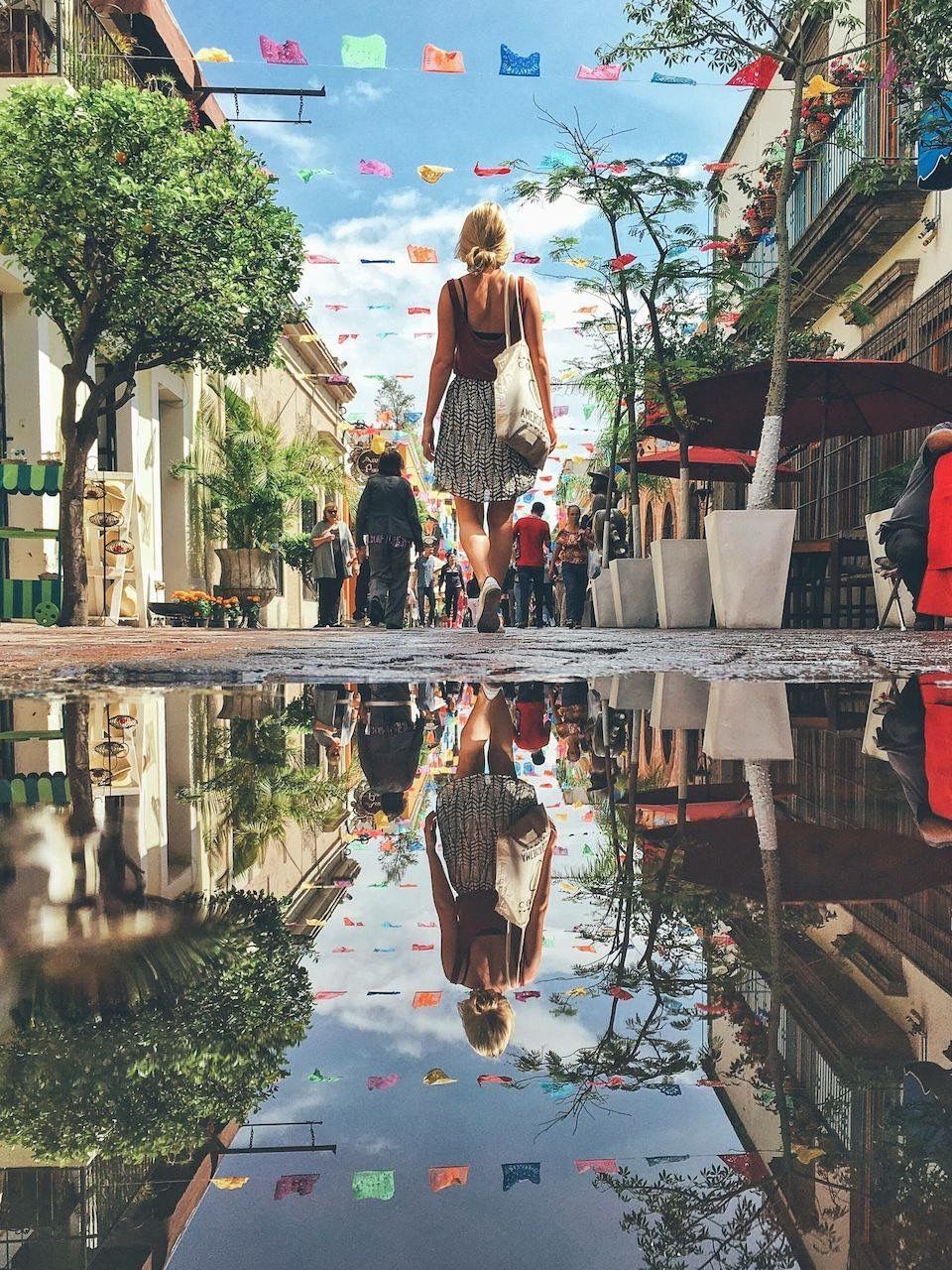 Low angle view of woman walking by puddle on street