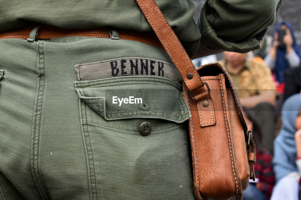 Midsection of man with brown shoulder bag