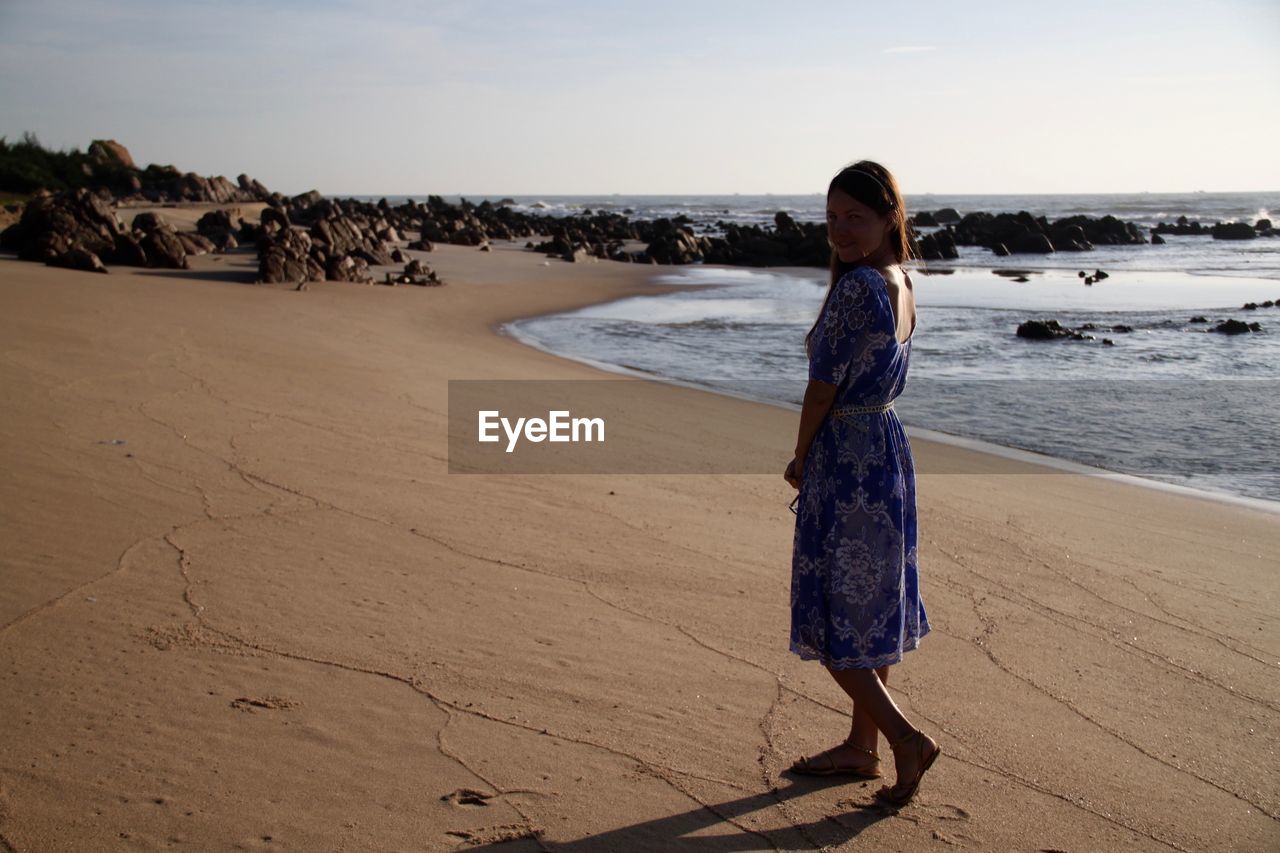 Side view of woman standing at beach