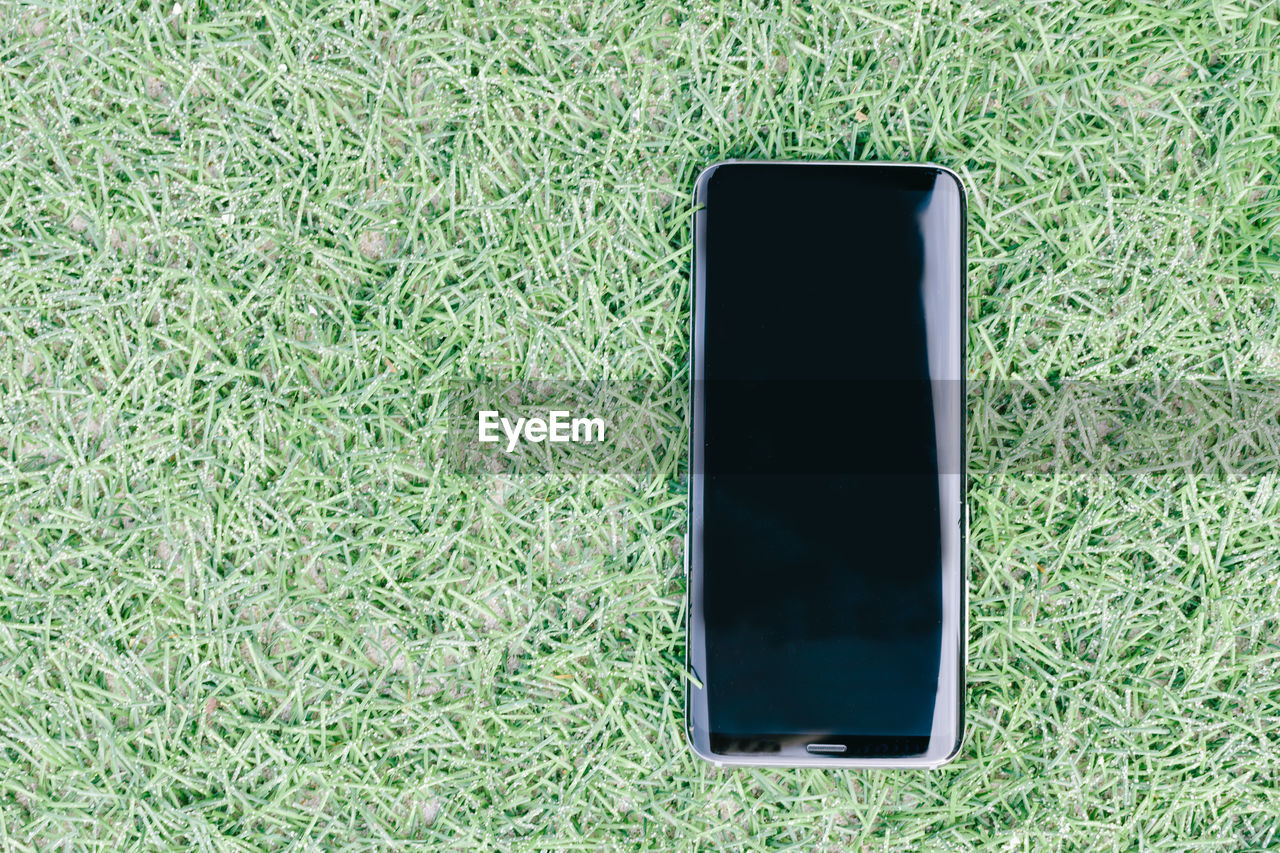 High angle view of smart phone on grassy field