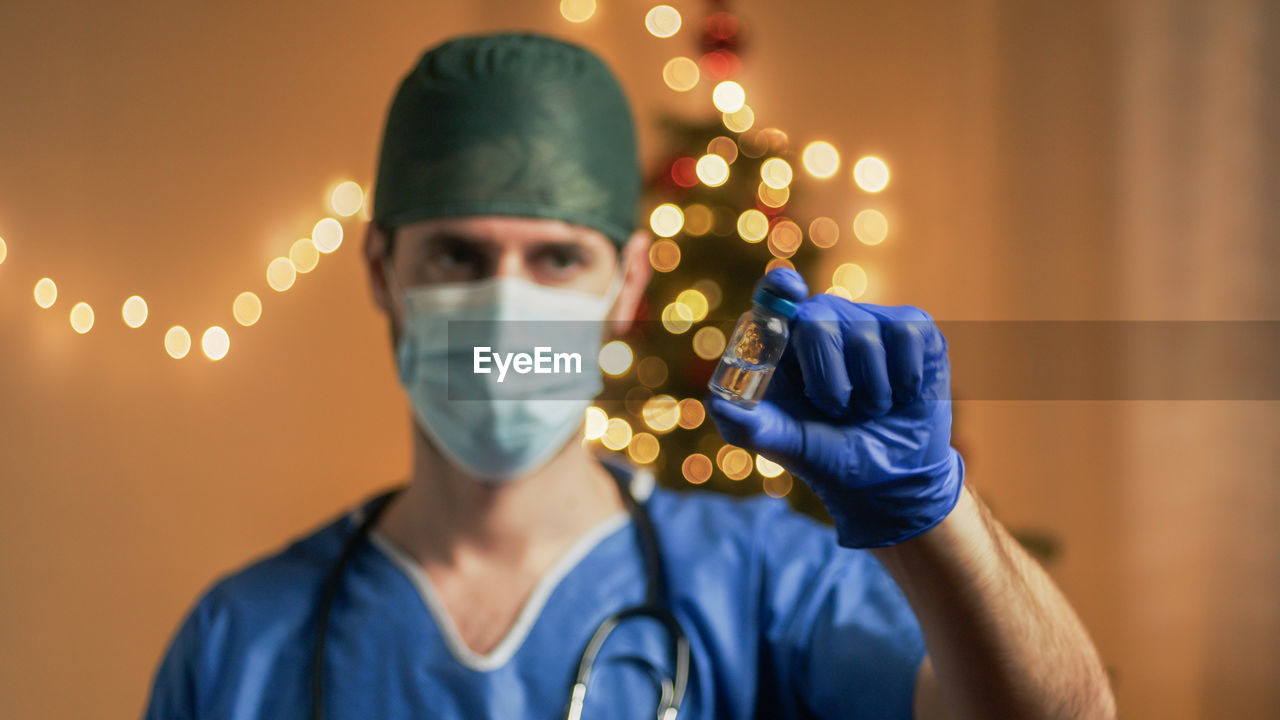 Doctor with vaccine on christmas background