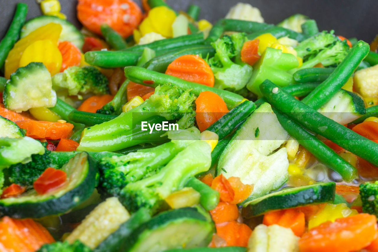 Crunchy vegetable pan with broccoli, corn, carrots , zucchiniand small pieces of pepper in a pan.