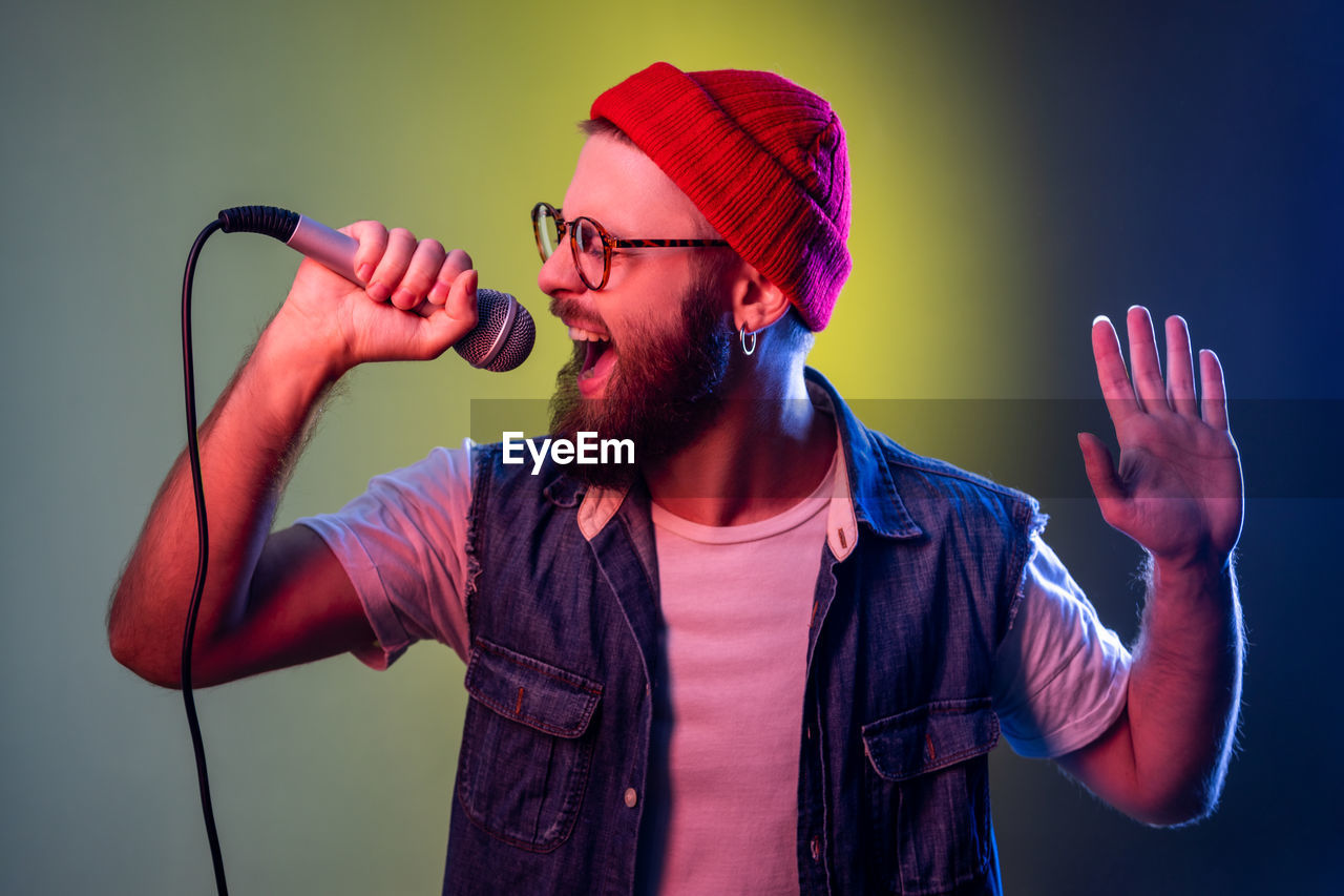 Man screaming on mic against green background