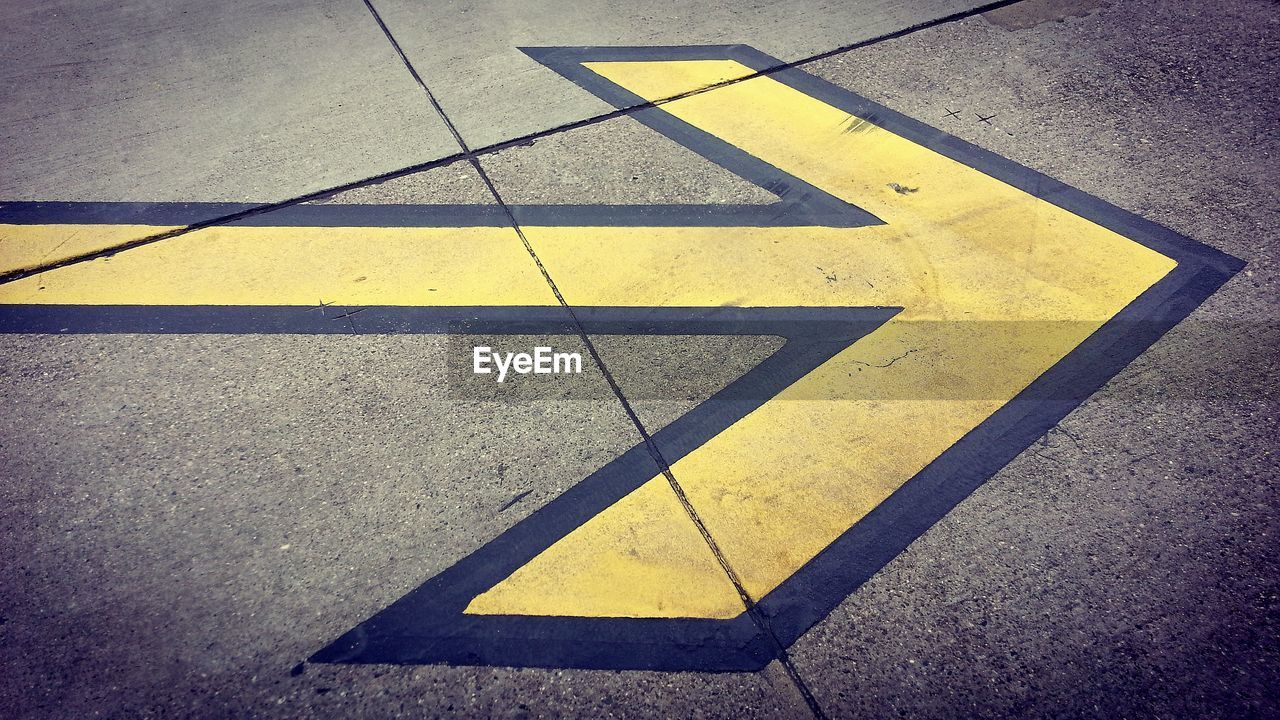 yellow, sign, line, road, symbol, guidance, road marking, marking, communication, circle, arrow symbol, transportation, triangle, no people, directional sign, city, light, high angle view, street, road sign, asphalt, shadow, blue, day, number, warning sign, outdoors
