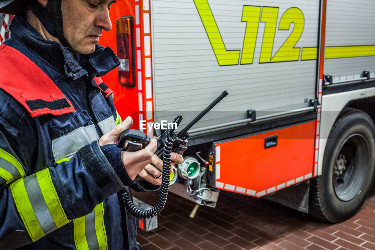 Firefighter using walkie-talkie by fire engine