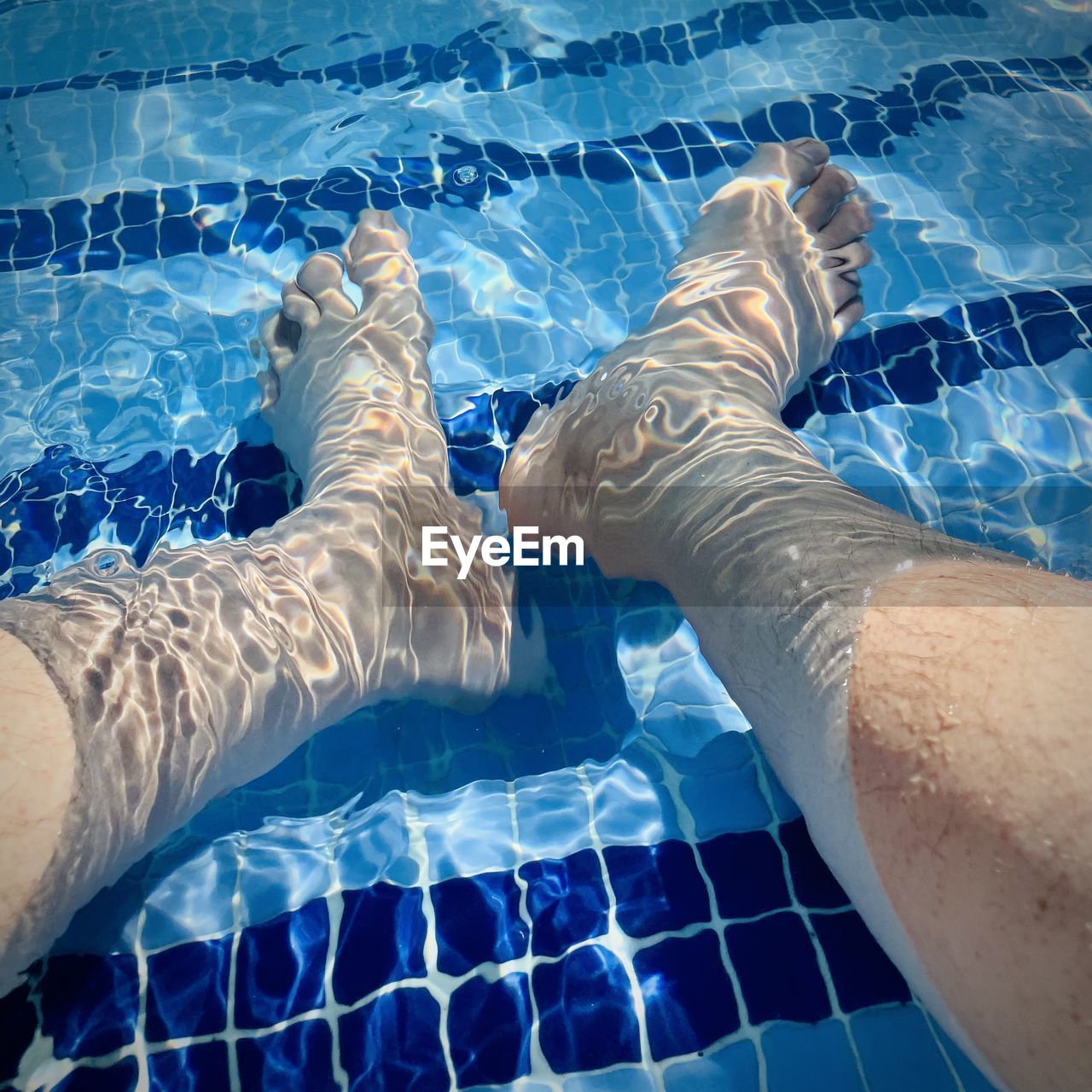 swimming pool, blue, water, human leg, low section, swimming, lifestyles, nature, personal perspective, adult, one person, tile, limb, human limb, leisure activity, human foot, high angle view, men, day, outdoors, sunlight, women, rippled