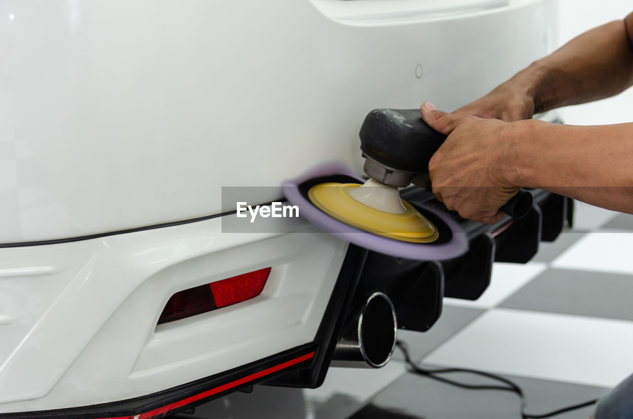 Cropped hands of mechanic polishing car in garage