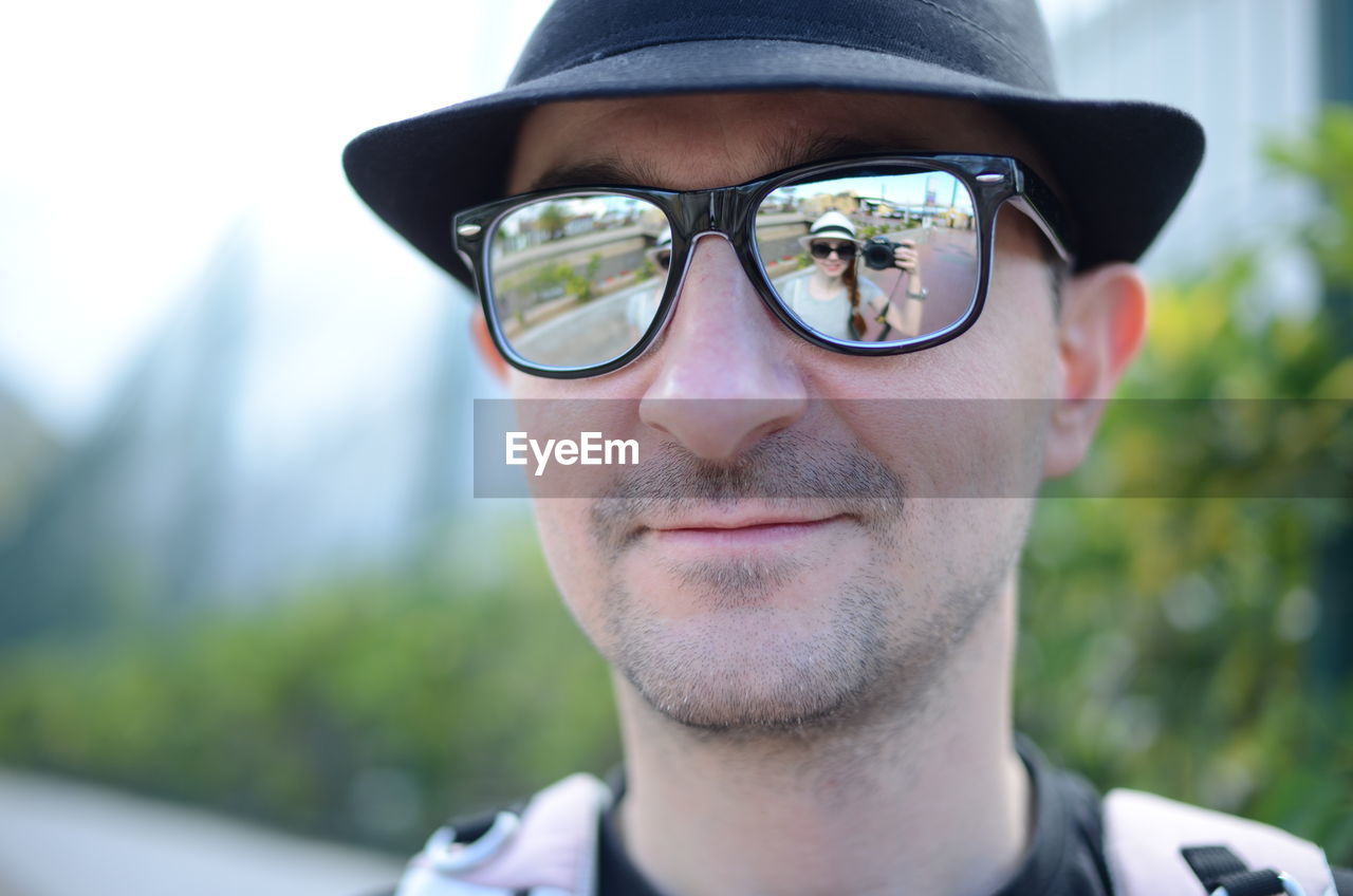 Reflection of woman on man sunglasses while photographing