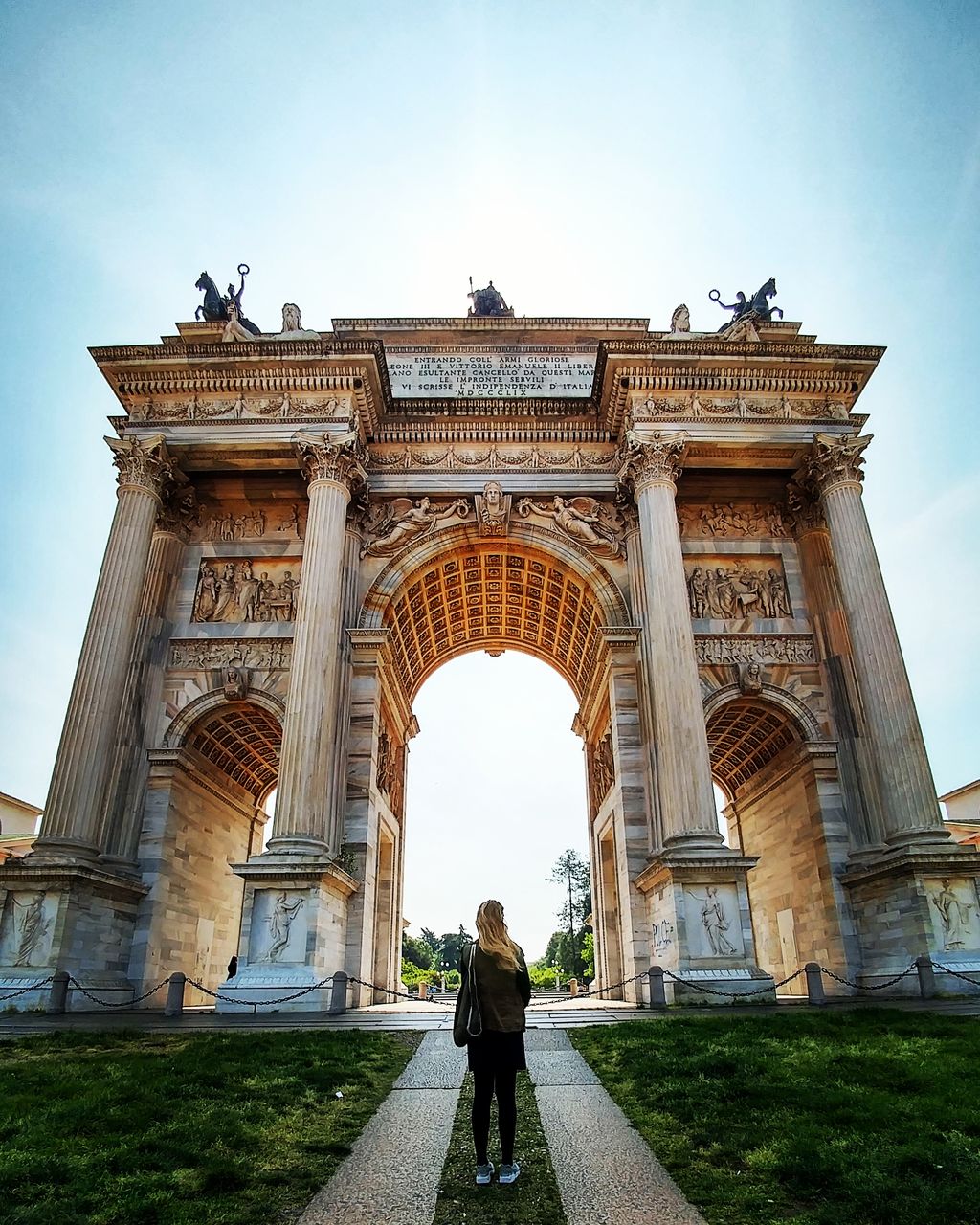 Rear view of woman standing at triumphal arch against sky