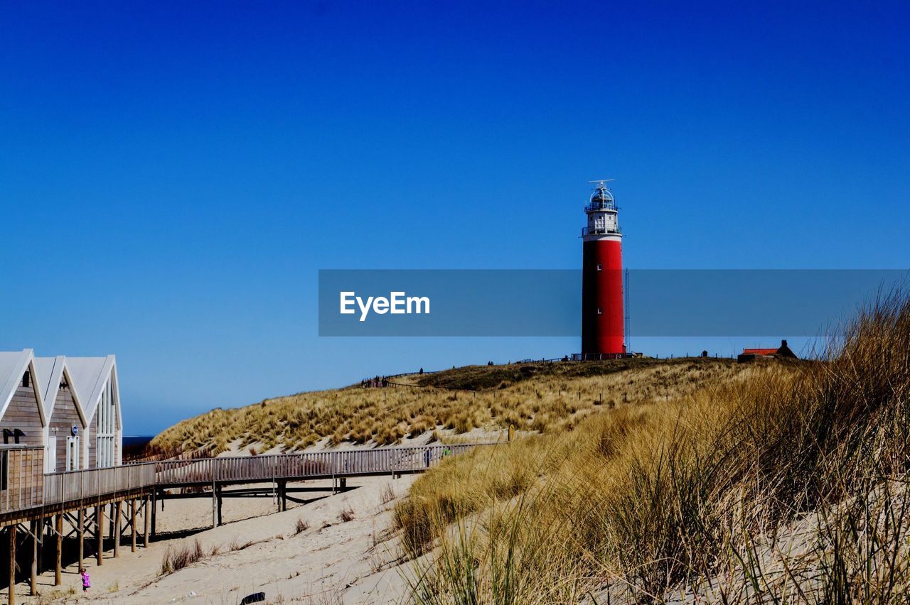 LIGHTHOUSE BY SEA AGAINST CLEAR SKY