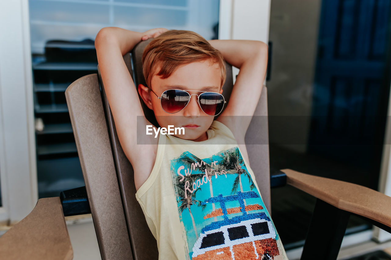 PORTRAIT OF BOY WEARING SUNGLASSES AT HOME